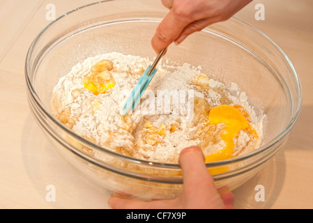 woman whisking eggs and flour in a bowl making a cake Stock Photo