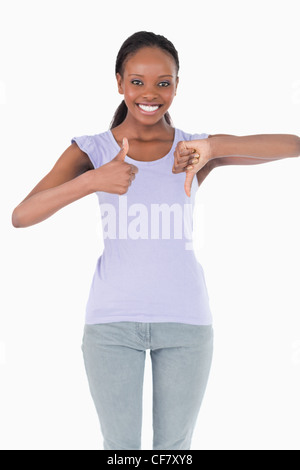 Close up of woman giving one thumb up and one down on white background Stock Photo