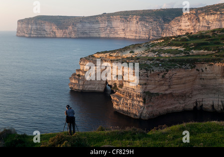 A photographer taking pictures of the sweeps of cliffs that girdle Gozo's south coast. Stock Photo