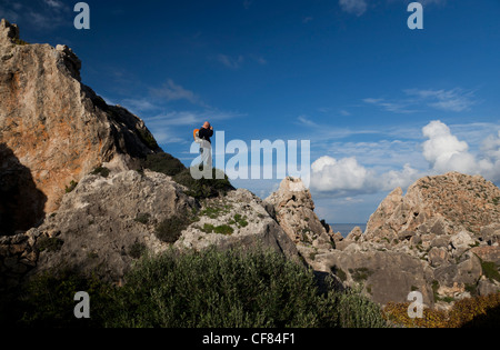 A trekker takes picture of the dramatic tumble of massive boulders at Rdum Il-Kbir on Gozo's north coast. Stock Photo