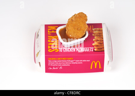 Container of McDonald's chicken McNuggets with a chicken piece on top of packaging in dipping sauce on white background cut out Stock Photo