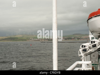 View from a sea ferry deck with rescue boat in foreground and wind farm on horizon in distance in Scotland