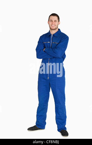 Smiling young mechanic in boiler suit with arms folded Stock Photo