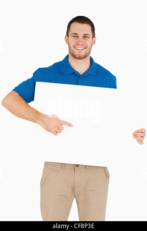 Smiling young salesman pointing at banner in his hands Stock Photo