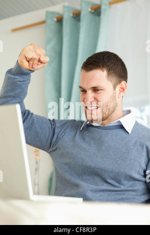 Businessman smiling and raising his fist in the air in office building ...