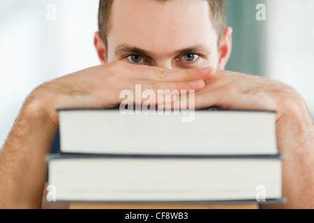 Student hiding behind a pile of books Stock Photo