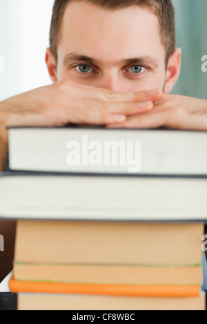 Close up of student hiding behind a pile of books Stock Photo