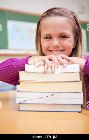 Happy schoolgirl posing with a stack of books Stock Photo - Alamy