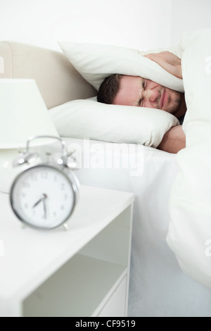 Portrait of a young man covering his ears with a pillow Stock Photo