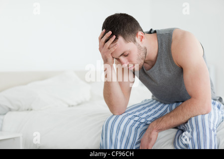 Exhausted man sitting on his bed Stock Photo