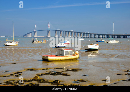 Small boats at low tide and the big bridge of Saint Nazaire at Saint Brevin les Pins in France Stock Photo