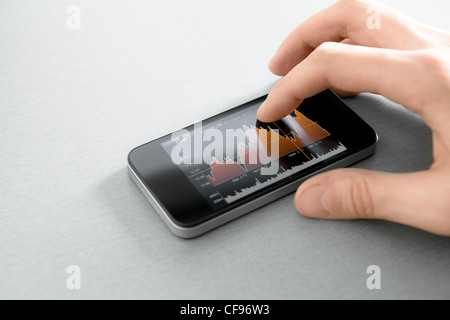 Hand touching stock market chart on mobile smart phone. Stock Photo