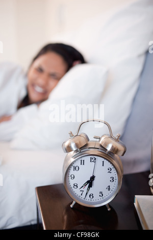 Alarm clock ringing next to woman in bed Stock Photo