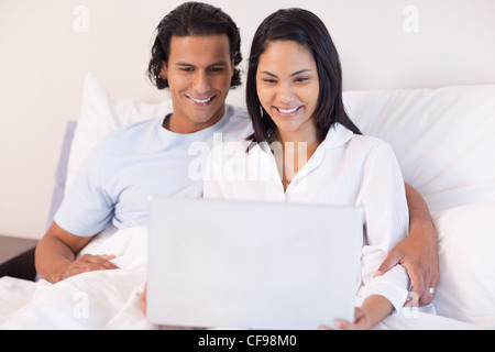 Couple sitting on the bed with their laptop Stock Photo