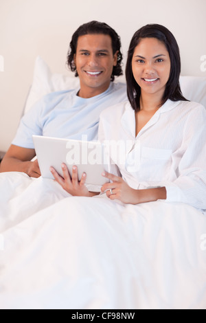 Couple using tablet pc in their bed Stock Photo