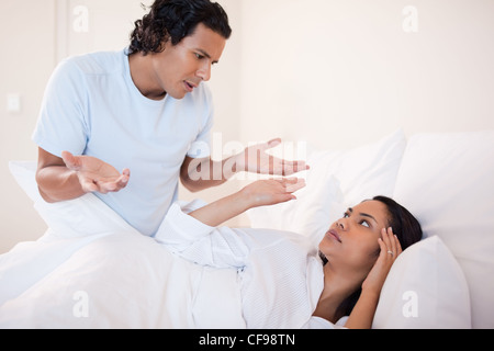Couple is lying in bed and arguing. The woman is angry with the man ...