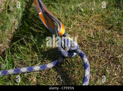 A climbers knot tying a rope to a screwgate attached to a sling at an anchor point at Auchinstarry Quarry, Scotland Stock Photo