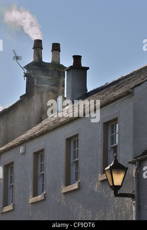 Village house in Scotland with sliding sash windows, slate roof, and smoke issuing from chimney pot. Stock Photo