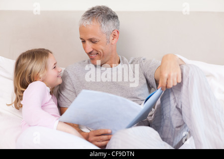 Happy father reading a story to his daughter Stock Photo