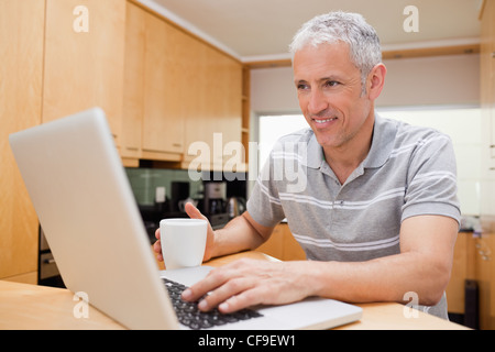 Man using a laptop while drinking tea Stock Photo