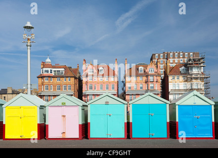 Brightly coloured beach huts on Brighton & Hove seafront with period buildings behind Stock Photo