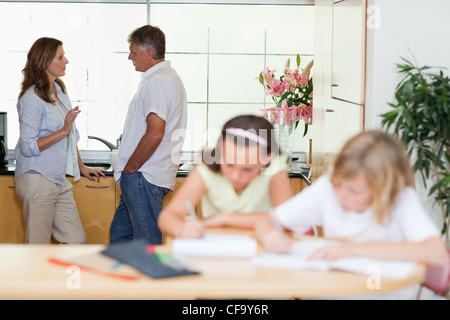 Parents talking with children doing homework in front of them Stock Photo