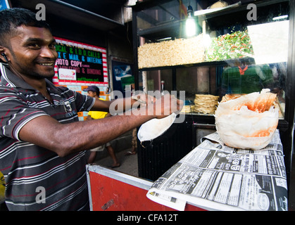 A local cook in a small hole in the wall restaurant  preparing Apams - rice pancakes. Stock Photo