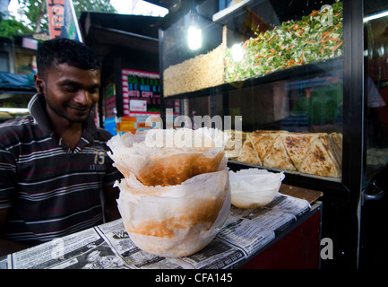 A local cook in a small hole in the wall restaurant  preparing Apams - rice pancakes. Stock Photo