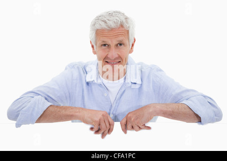 Portrait of a smiling mature man standing behind blank panel Stock Photo
