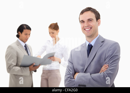 Smiling young businessman with talking colleagues behind him Stock Photo