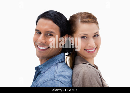 Side view of smiling couple standing back to back Stock Photo