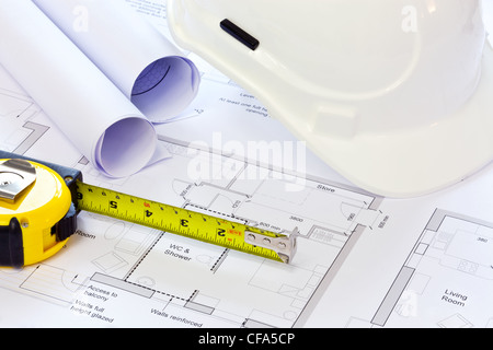 Still life photo of some building plans with a hard hat and tape measure. Stock Photo