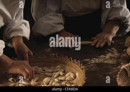 Chefs rolling gnocchi dough in kitchen Stock Photo