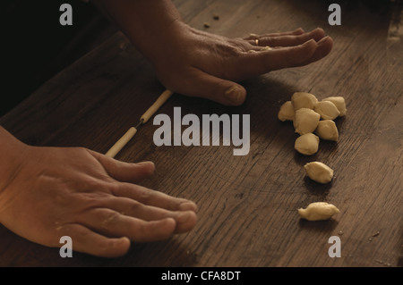 Cook rolling gnocchi dough in kitchen Stock Photo