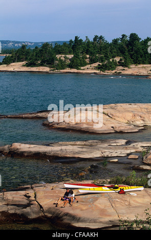 Couple with sea-kayaks rest on island in Georgian Bay near Kilarney, Ontario, Canada. Stock Photo