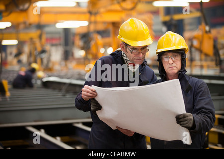 Workers reading blueprints in shipyard Stock Photo