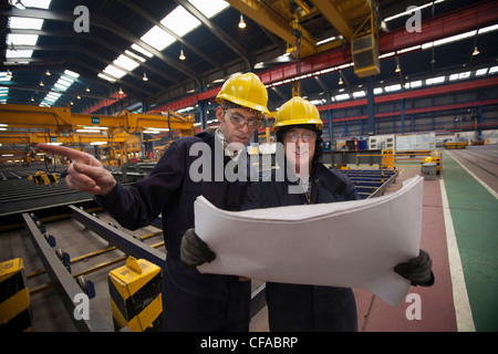 Workers reading blueprints in shipyard Stock Photo