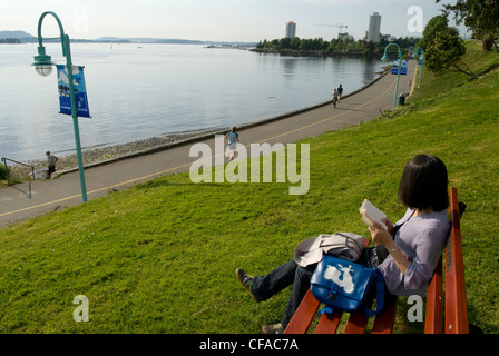 Woman reading a book along Harbour front walkway. Nanaimo, British Columbia, Canada. Stock Photo