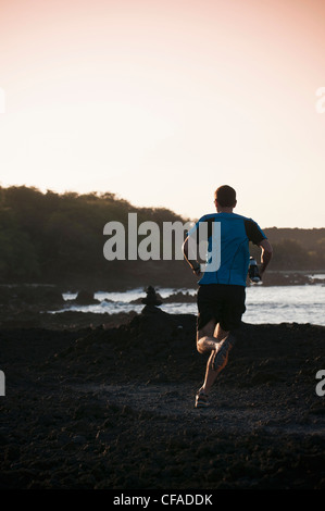Man running on rocky beach Stock Photo