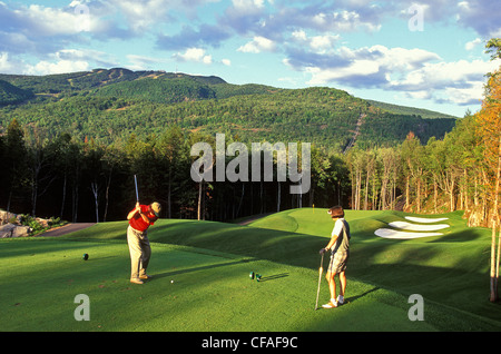 Young couple playing golf at Mont Tremblant Resort, north of Montreal, Quebec, Canada. Stock Photo