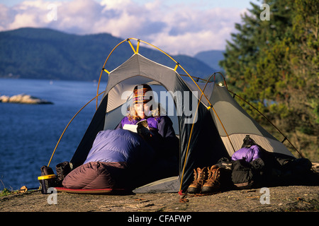 Woman reads a book in her tent, Lighthouse Park, West Vancouver, British Columbia, Canada. Stock Photo