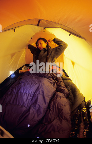 A young woman waking and stretching in a tent in Jasper, Alberta, Canada. Stock Photo