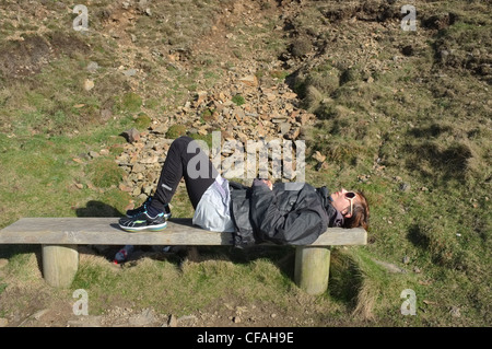 A female jogger takes a break in the winter sun of Cornwall to absorb the sun. Stock Photo