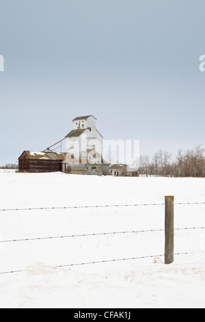 Barbed wire fence in front of an abandoned grain elavator and field in winter time, Bardo, Alberta, Canada. Stock Photo