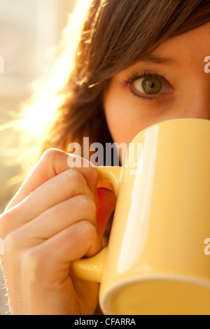 Woman drinking from yellow mug on a summers morning. Looking. Stock Photo