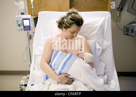 36 year old woman lying in hospital bed breastfeeding her newborn, Chateauguay, Quebec, Canada Stock Photo