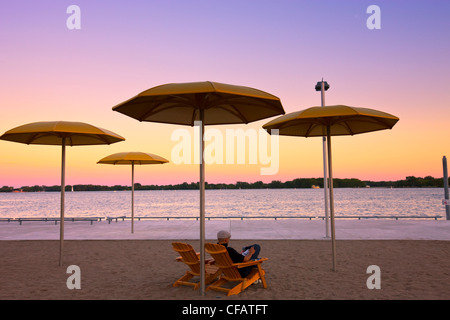 Man sitting on the Toronto waterfront beach at dusk, Ontario, Canada. Stock Photo