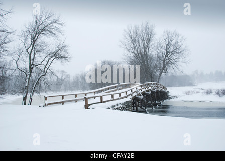 Old north bridge where the American revolution was started. Covered in snow with minuteman statue in background. Stock Photo