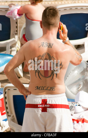 Englishman with an image of the George Cross tattooed on his back standing by the pool on holiday Stock Photo