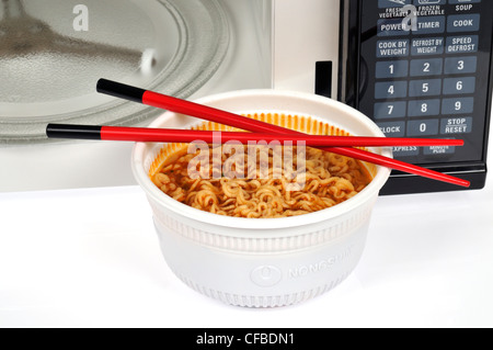 Oriental noodles in front of microwave oven with chopsticks Stock Photo